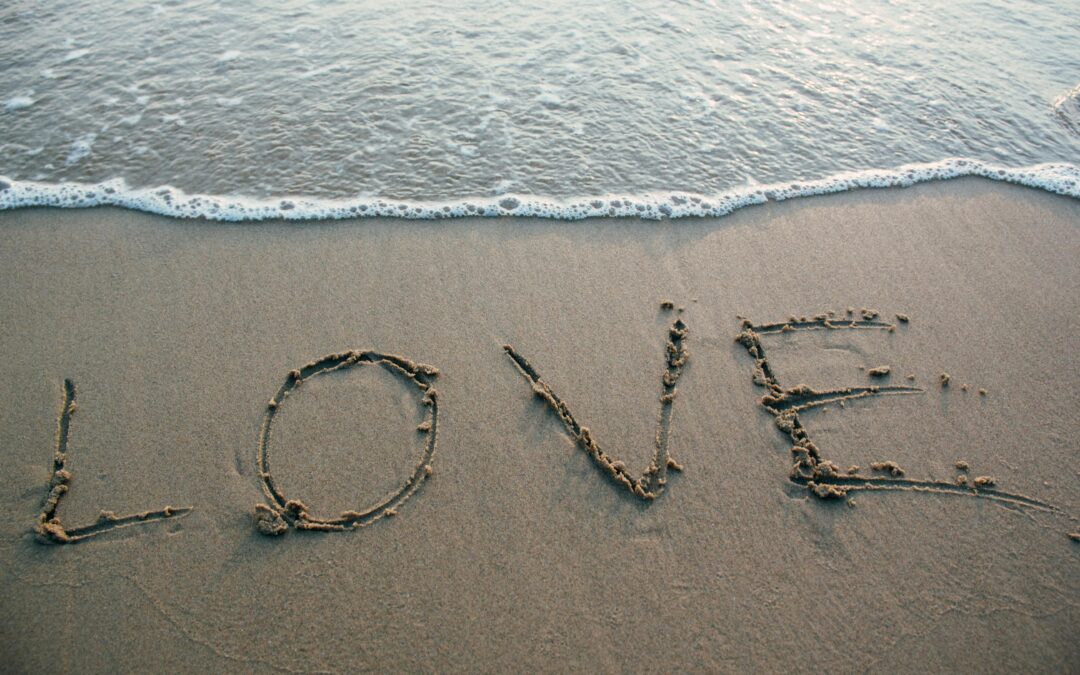 Sand on beach, with the word LOVE written in the sand.